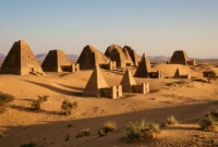 Kingdom of Kush pyramids at Meroë rising from desert sand under afternoon sunlight