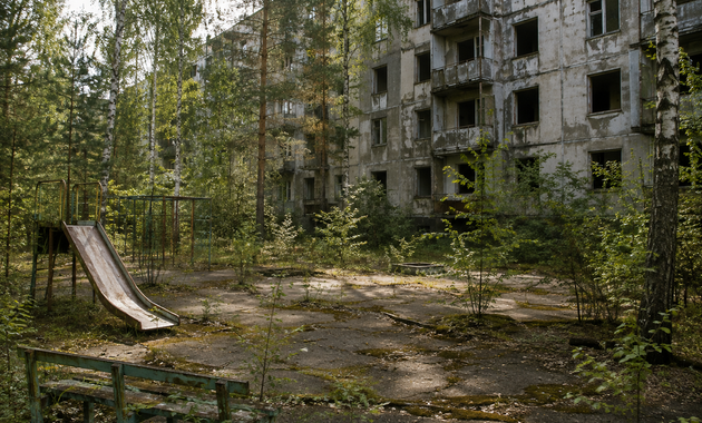 Nature reclaiming a Pripyat apartment courtyard decades after evacuation